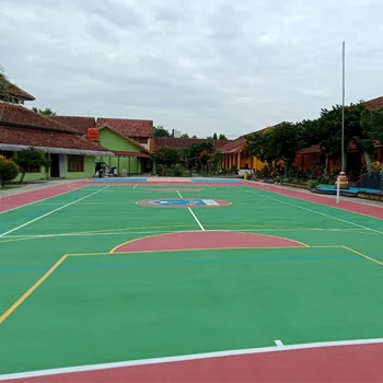 Lapangan basket outdoor di lingkungan sekolah dengan permukaan berwarna hijau dan merah