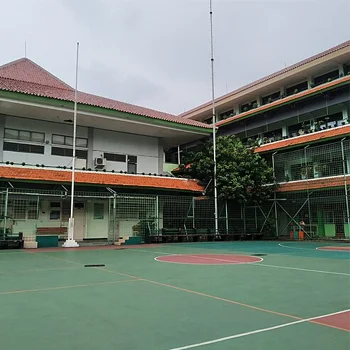 Lapangan basket outdoor di lingkungan sekolah dengan permukaan acrylic dan bangunan sekolah