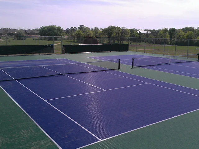 Lapangan tenis outdoor dengan permukaan lapangan berwarna biru dan hijau